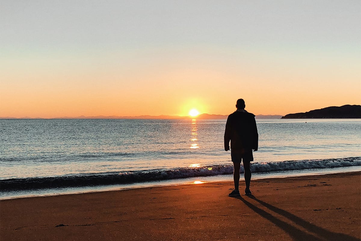 Man staring at a sunrise at the beach