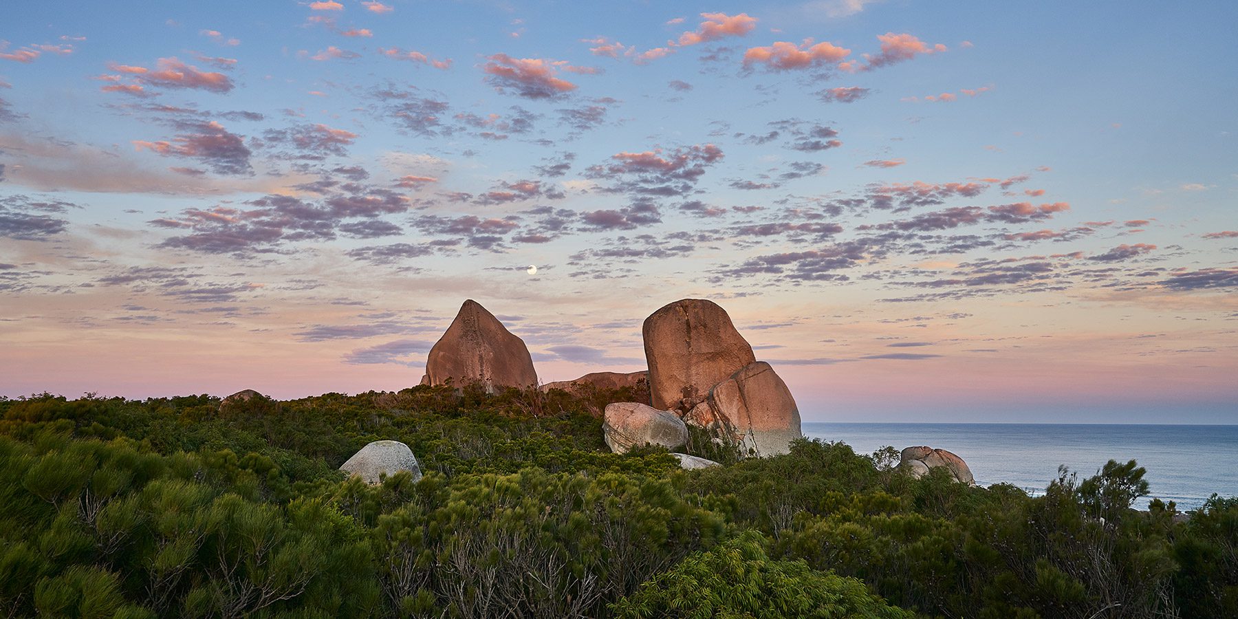 Glowing rocky sculptures on the coastline, under a colourful sky. Bibbulmun Track, Western Australia