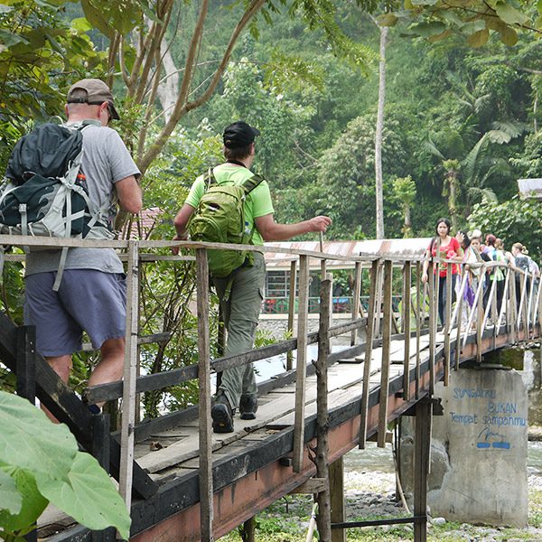 People crossing a wodden bridge in Sumatra