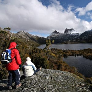 Hikers resting on an lookout admiring the view of Cradle Mountain in the distance