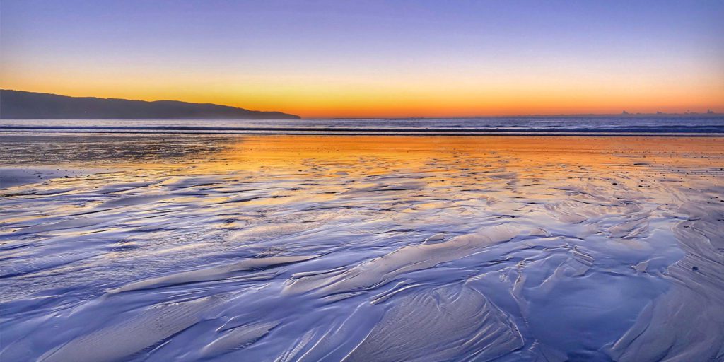 Sunset: Tracks of water receding on the sand at Apollo Bay, Victoria, Australia