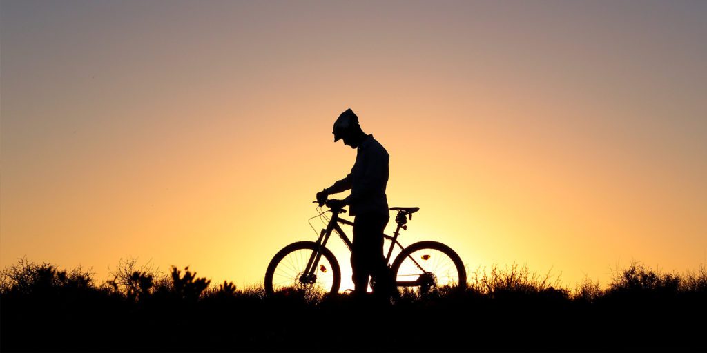 Cyclist silhouetted by setting sun