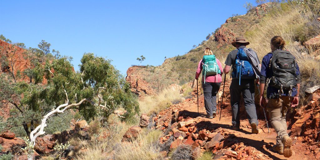 Trekkers following a dusty path through the red rocky outback