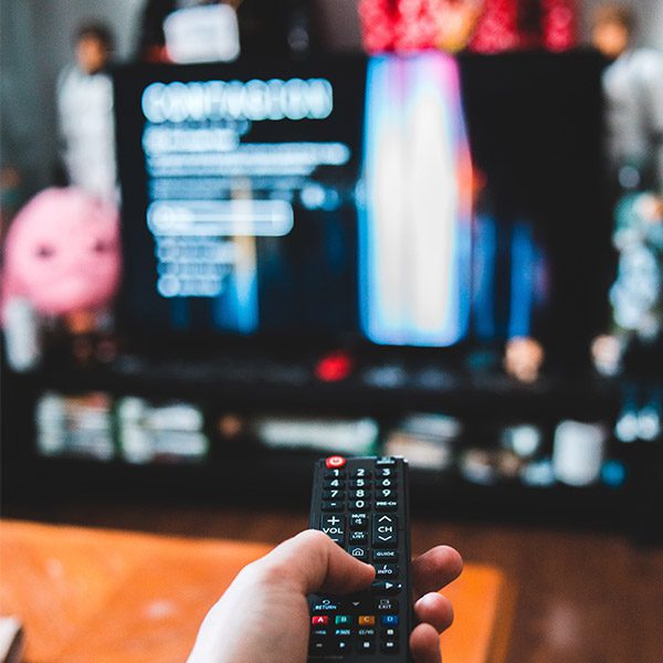 A hand holding a remote and pointing at the tv
