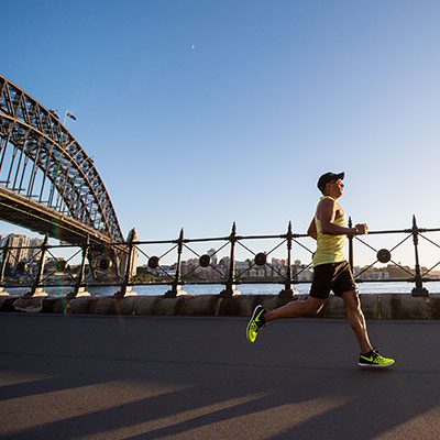 Man running along a path with the Sydney Harbour Bridge in the background