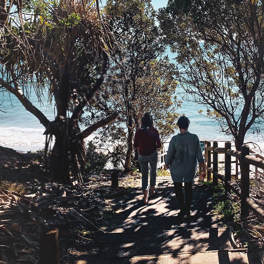 Two people following a coastal trek on a sunny day