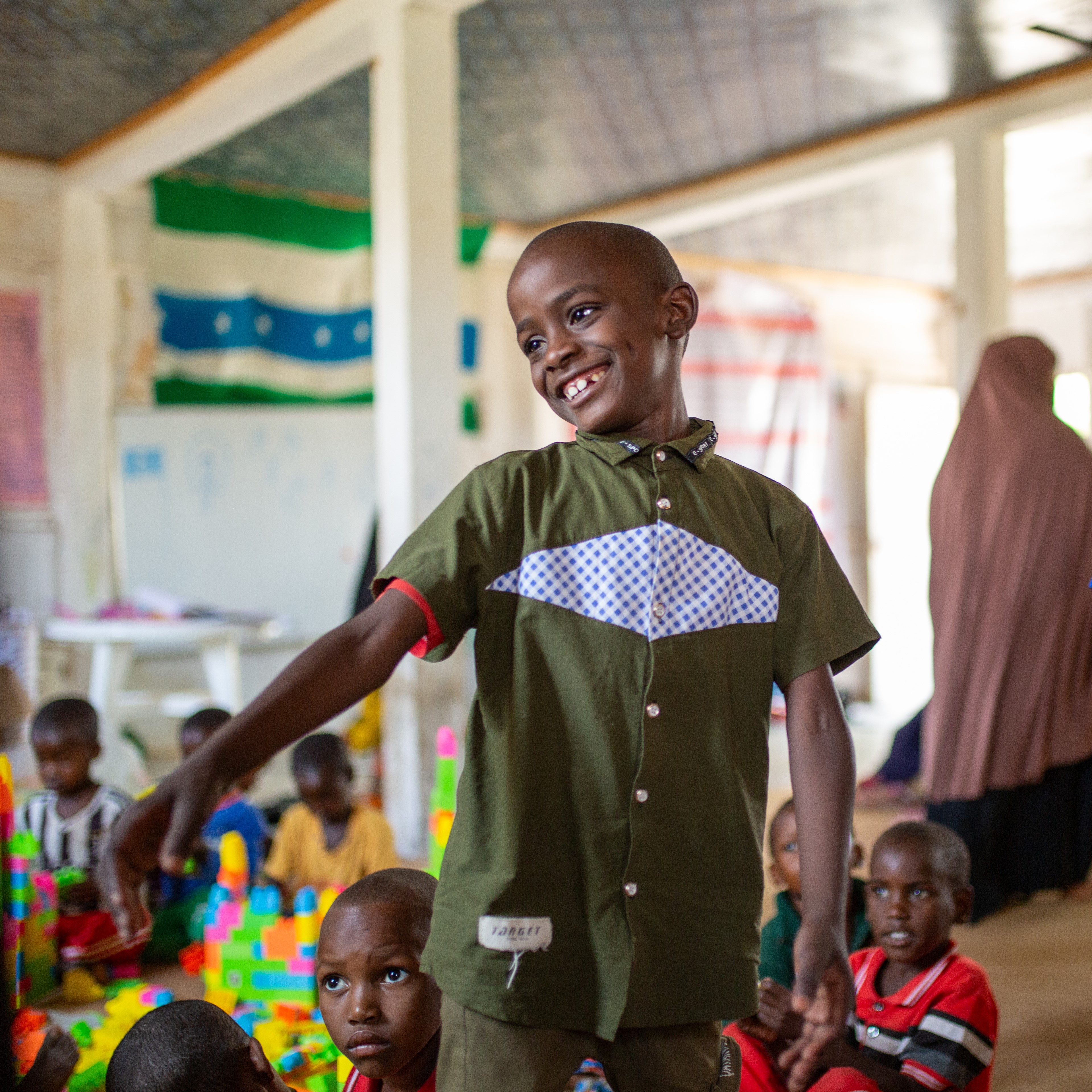 Salad playing with children at the child friendly space. 

Salad, a 7-year-old boy, lives with his parents and three siblings in an Internally Displaced Persons (IDP) camp on the outskirts of Qardho, Somalia. Despite the hardships, he dreams of seeing his community transformed into a green haven full of trees. His family was forced to relocate to the IDP camp after losing their farm due to drought and locust infestations.

Salad finds joy in the child-friendly space within the camp, where he loves to draw. "I like drawing houses and cars," he said. "I want to become a teacher and help people better their lives and futures through education," he added, revealing his aspirations.
He also enjoys playing football with his friends in the camp, particularly on Fridays. "When I get hungry, my throat dries up and my stomach starts making noises, making it hard for me to continue playing," Salad shared.
Despite the challenges he faces, Salad remains optimistic and hopeful, drawing strength from his dreams and the simple joys of childhood.