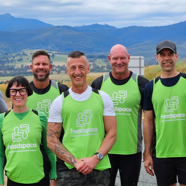 Team of smiling faces with headspace singlets, mountains rise up in the distance