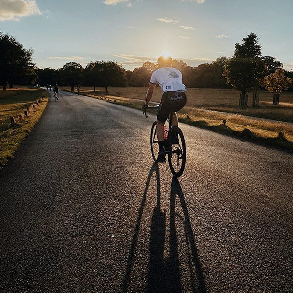 Cyclist going into the distance on a wide road at dusk