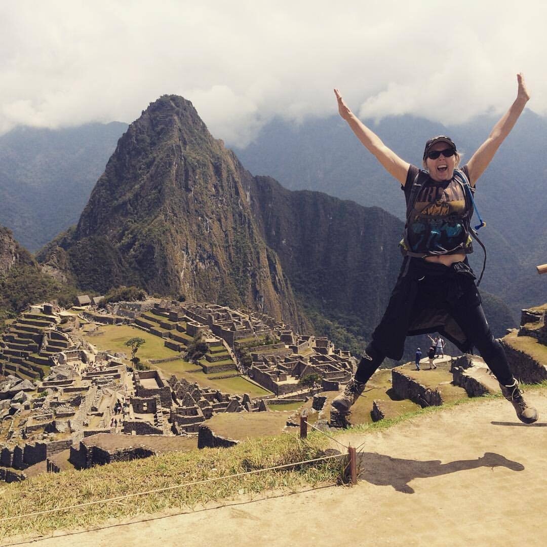 Michelle Faithfull, Team Leader, doing a star jump in front of machu picchu